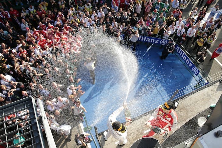 A F1 podium with people spraying champagne.